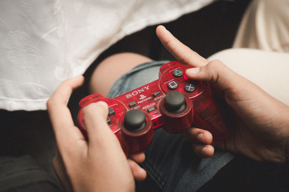 Games Consoles — stock photo by Mahmoud Yahyaoui via Pexels (https://www.pexels.com/photo/close-up-of-hands-holding-red-playstation-controller-28920054/)