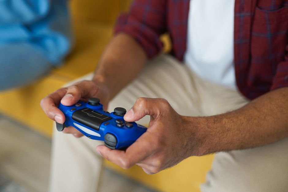 Games Consoles — stock photo by VAZHNIK via Pexels (https://www.pexels.com/photo/a-person-holding-a-wireless-game-controller-7871558/)